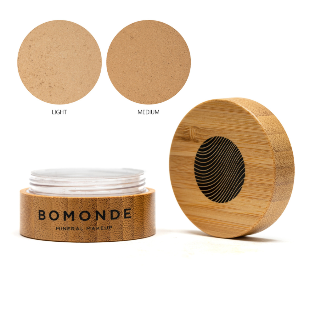 A round bamboo pot of Bomonde Loose mineral powder concealer, lid unscrewed and placed upright next to the pot - two swatches in the top right corner in shades light and medium