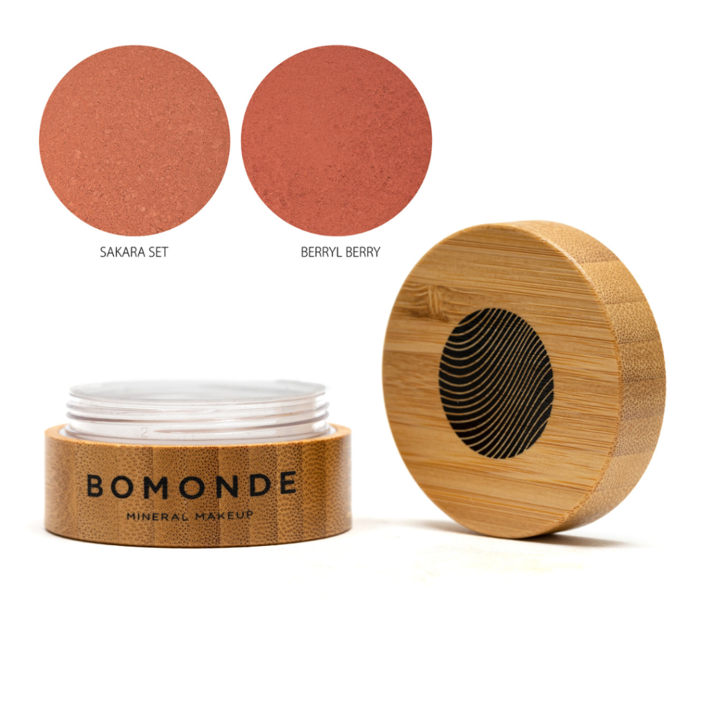 A round bamboo pot of Bomonde powder blusher, lid unscrewed and placed upright next to the pot - two swatches in the top right corner in shades Sakara set and berry berry