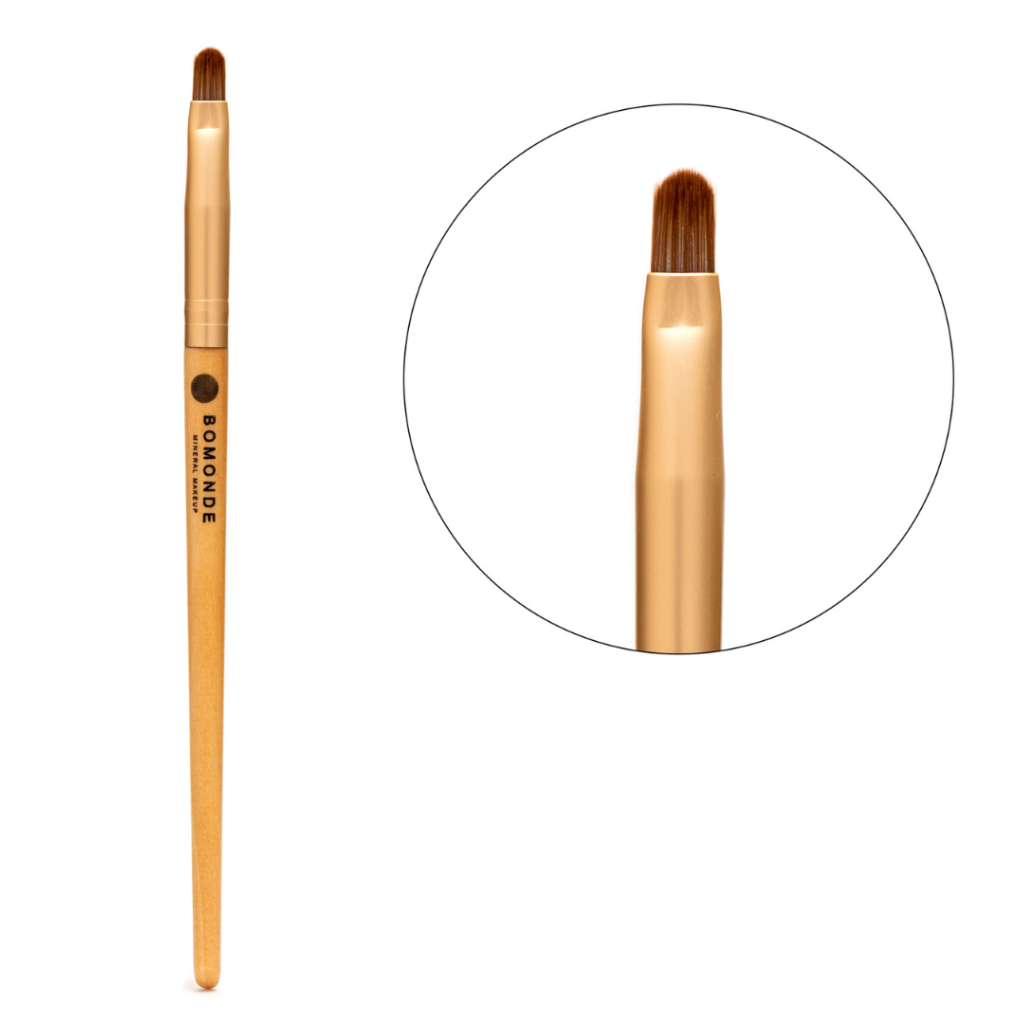 photo of bomonde's small flat eyeshadow brush on a white background. on the left you can see the chestnut coloured bristles of the brush which are angled to add definition and contouring to your make up looks. there is a gold metal texture to help join the bristles to the yellow bamboo wooden handle which has the black bomonde logo printed on it. to the right of the image there is a close up of the cruelty free synthetic brush bristles in a circle