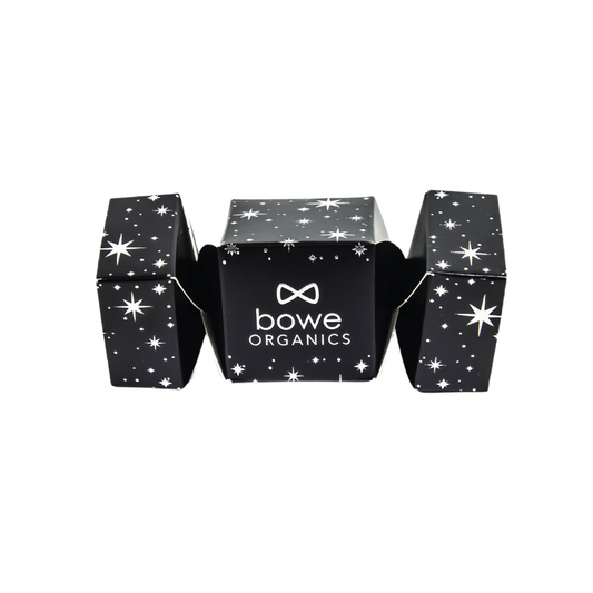 Bowe Lip Balm Christmas Cracker. A small black christmas cracker with white stars and sparkles set against a white background and labelled with bowe organics.