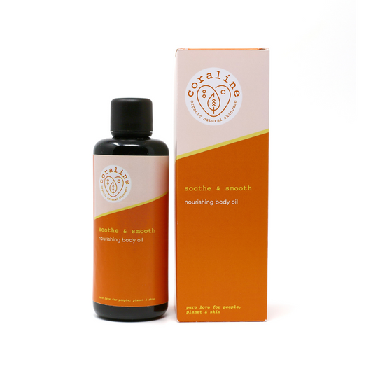 A glass bottle of soothe and Smooth nourishing body oil. stands next to its box. The bottle is black, with an orange label and white logo. The box features an orange design with white and yellow branding text highlighting the natural ingredients.
