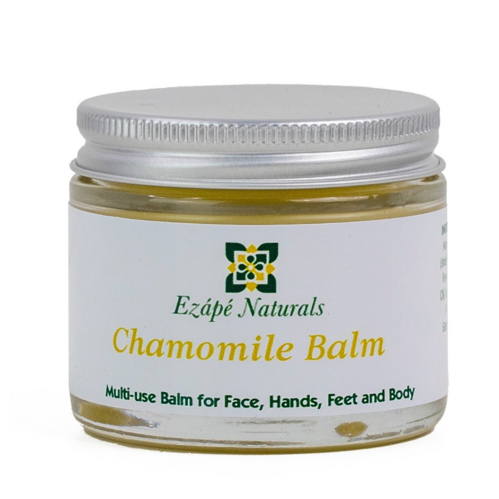 Large Chamomile balm which is handmade by ezape naturals is photographed on a white background. the multi use balm comes in a clear glass jar with a silver aluminium lid. the label is white and reads 'ezape naturals chamomile balm multi use balm for face, hands, feet and body’