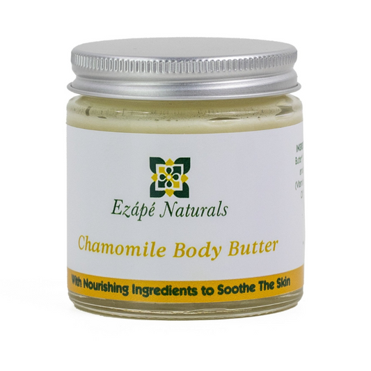 Chamomile body butter which is handmade by ezape naturals is photographed on a white background. the body cream comes in a clear glass jar with a silver aluminium lid. the label is white with a yellow coloured band along the bottom and reads ' ezape naturals chamomile body butter with nourishing ingredients to restore the skin'