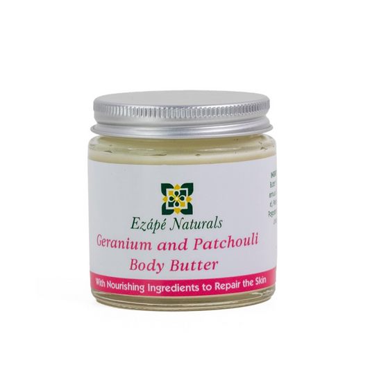 Geranium and Patchouli body butter which is handmade by ezape naturals is photographed on a white background. the body cream comes in a clear glass jar with a silver aluminium lid. the label is white with a pink coloured band along the bottom and reads ' ezape naturals geranium and patchouli body butter with nourishing ingredients to repair the skin'