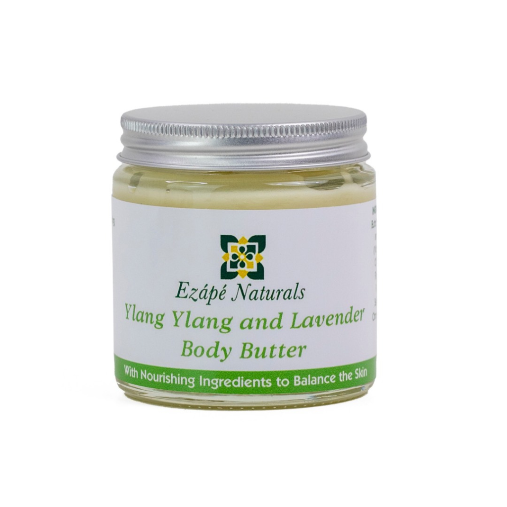 Ylang ylang and Lavender body butter which is handmade by ezape naturals is photographed on a white background. the body cream comes in a clear glass jar with a silver aluminium lid. the label is white with an green coloured band along the bottom and reads 'ezape naturals Ylang ylang and Lavender body butter with nourishing ingredients to balance the skin'