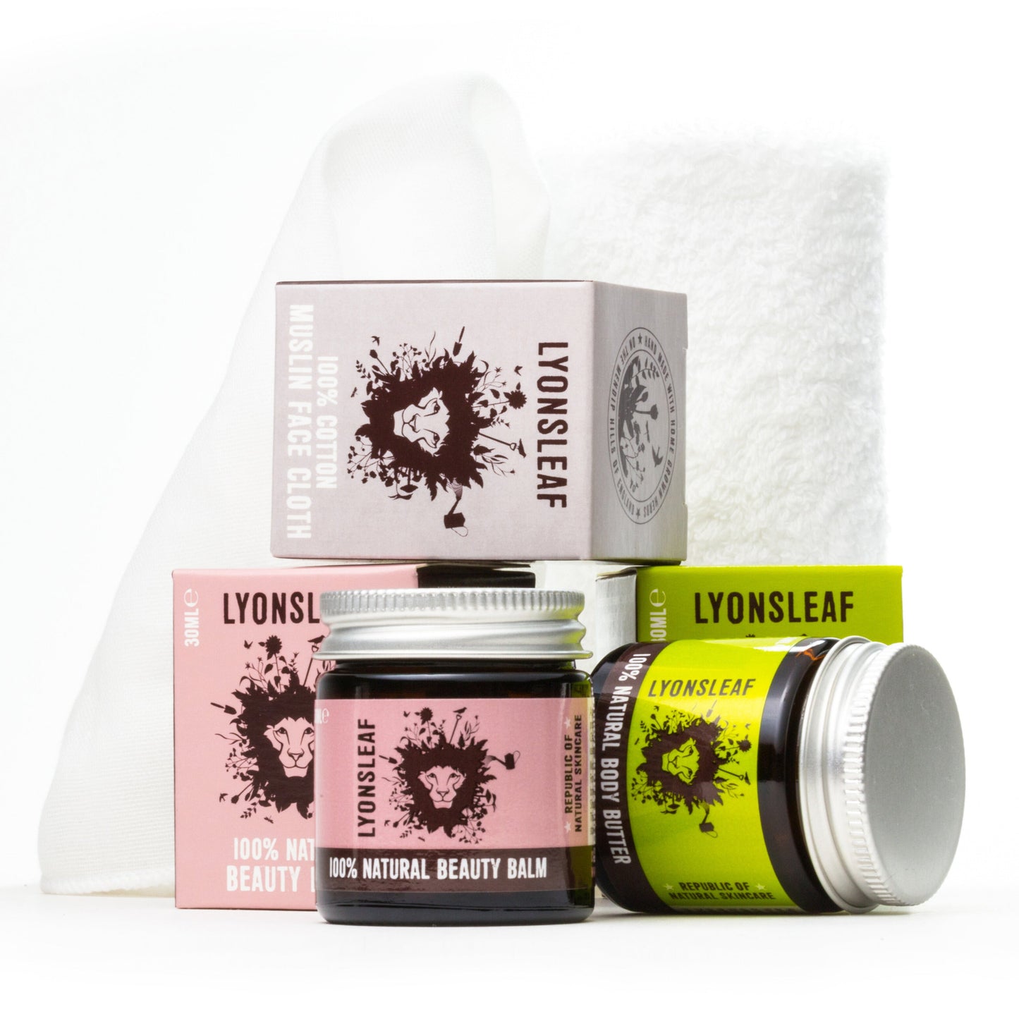 the contents of lyonsleaf's face and body natural skincare set. 100% natural beauty balm for hot cloth cleansing and moisturising, 100% cotton fluffy face cloth and body butter. the image shows the jars, boxes and cloth within the kit sitting at various angles