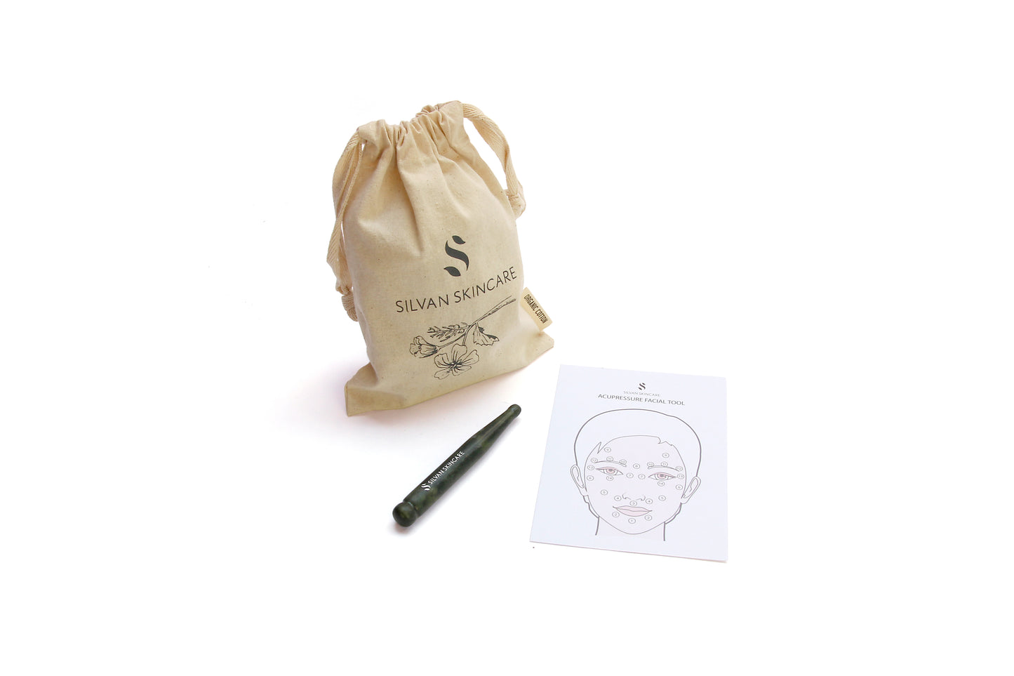 green jade acupressure wand photographed next to the cream cotton cloth bag and instruction sheet
