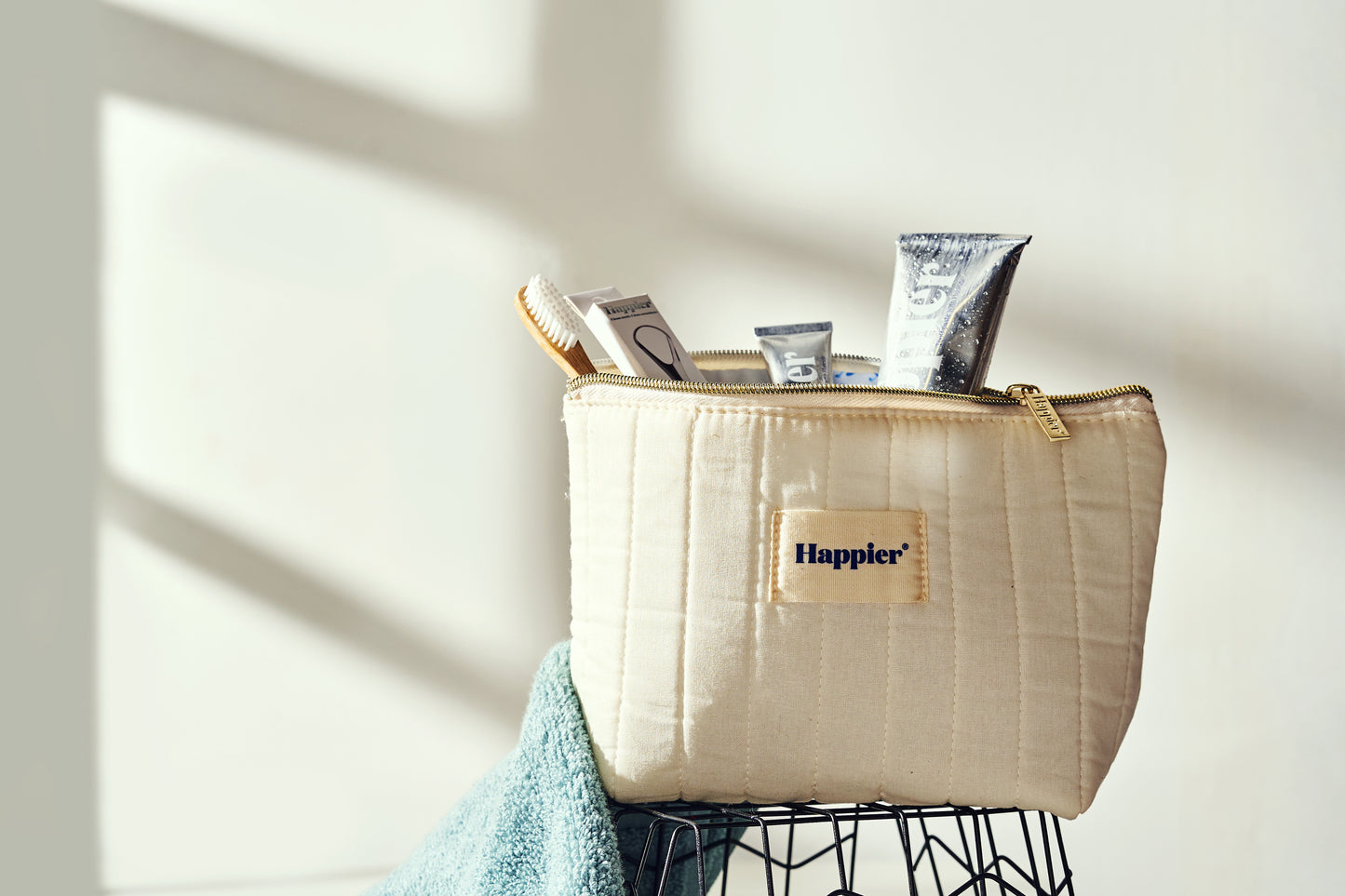 happier beauty natural dental products seen peeking out of a branded fabric washbag