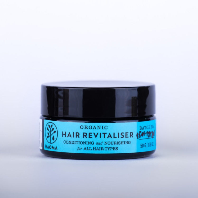 photo of a jar of organic hair revitalising treatment from haoma. The jar and plastic lid are black and there is a bright blue label on the front of the jar which reads 'organic hair revitaliser conditioning and nourishing for all hair types'