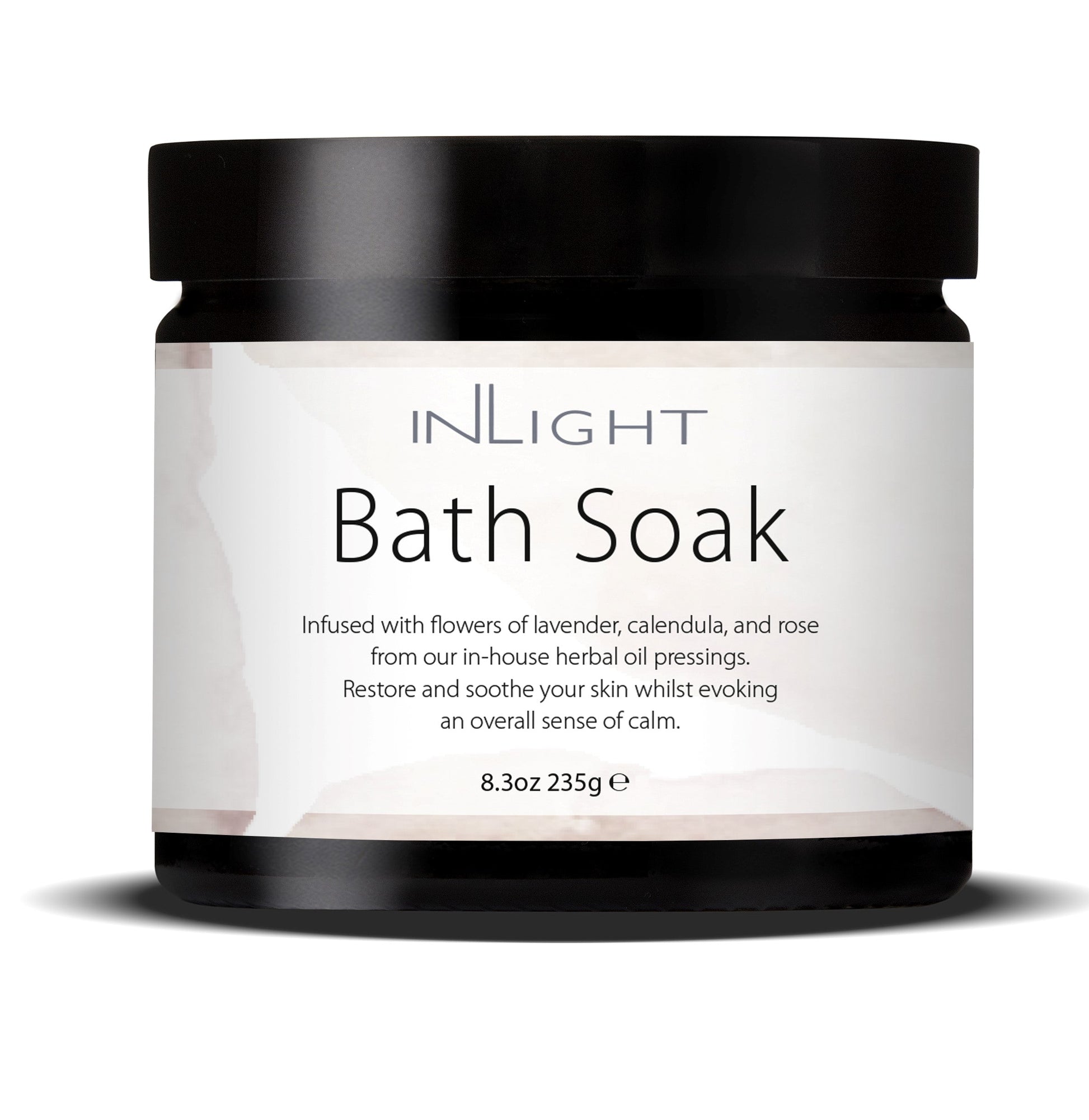 photo of inlight beauty bath soak in a black jar with black plastic lid and pinky white label which reads 'inlight bath soak infused with flowers of lavender, calendula and rose from our in-house herbal oil pressings. restore and soothe your skin whilst evoking an overall sense of calm'