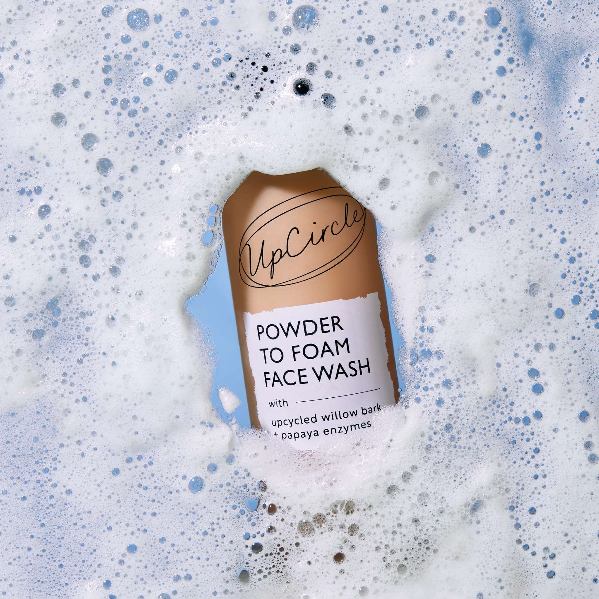 UpCircle Powder to Foam Face Wash bottle with foamy texture in the background