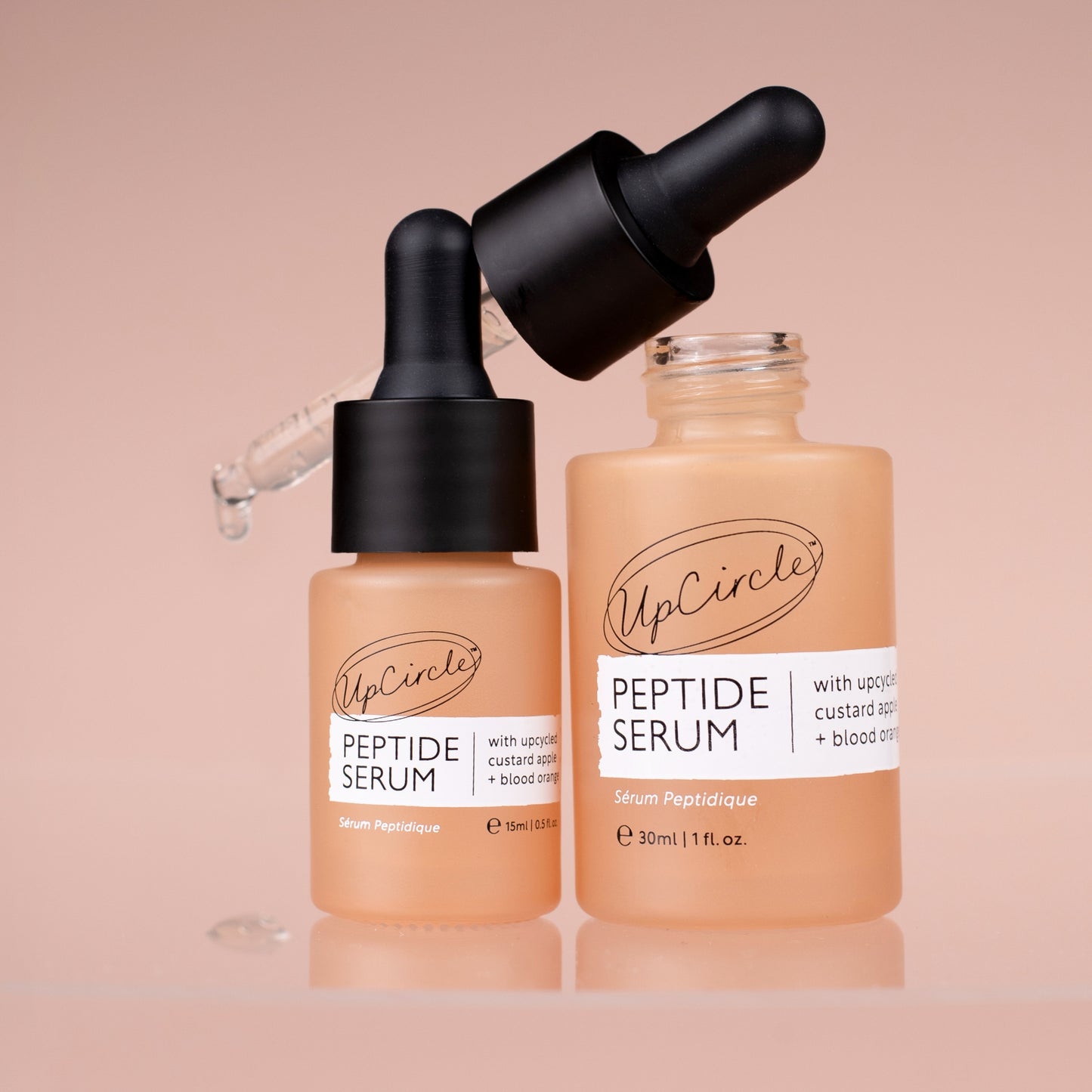 upcircle peptide serum in 2 sizes 10ml and 30ml. they are both in orange pipette bottles but the lid of the 30ml bottle is off and placed n top of the 2 bottles