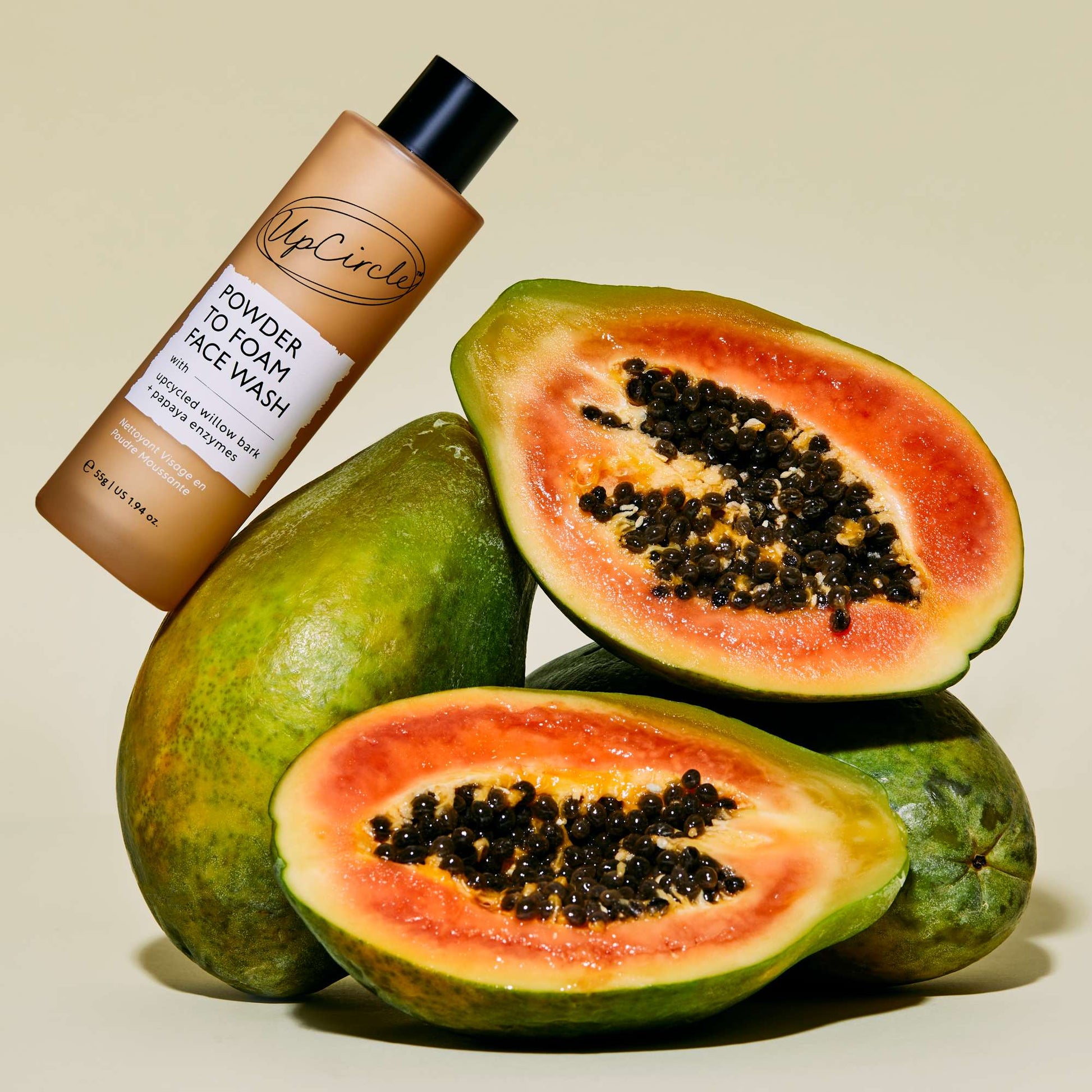 UpCircle powder to foam face wash with halved papaya on a beige background