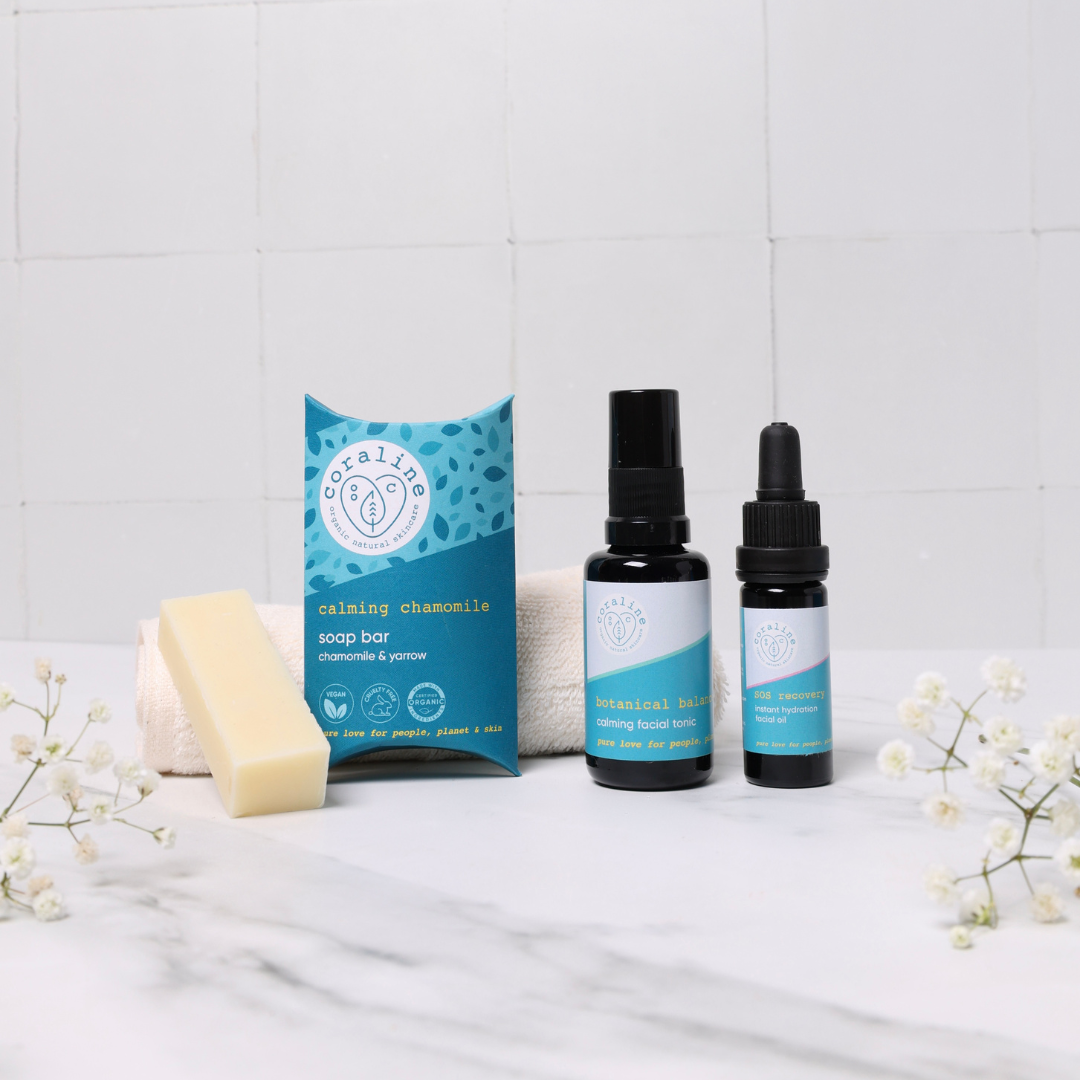 a creamy white slice of chamomile soap sits next to a spray bottle of calming face mist and a pipette bottle of soothing face oil for sensitive skin