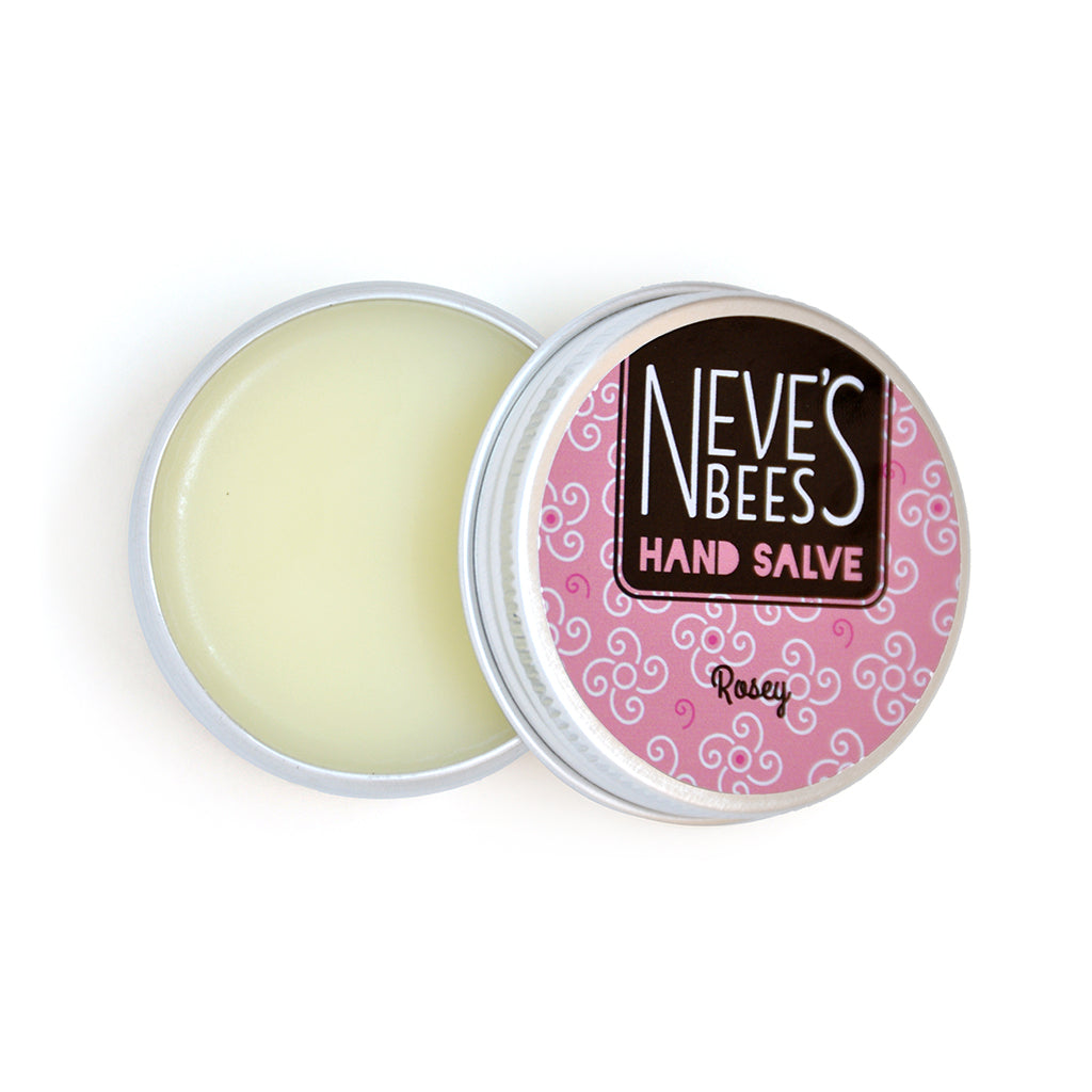 photo of neve's bees hand salve on a white background. the hand salve comes in an aluminium tin with a rose pink label on it that reads 'neve's bees hand salve rosey' there are graphics of swirly flowers in the background of the label. the tin is open and you can see the creamy coloured balm inside