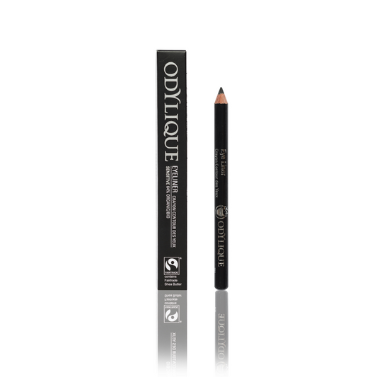 A black eyeliner pencil next to its packaging box which displays the brand name ‘Odylique’ in bold letters. the setting is on a reflective white surface with a white background.