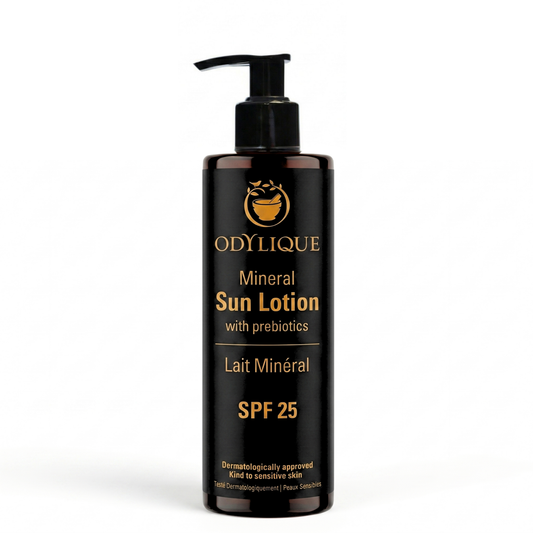 A bottle of Odylique Mineral Sun Lotion SPF 25 with a black pump dispenser and a black label featuring gold text and logo, set against a plain white background.