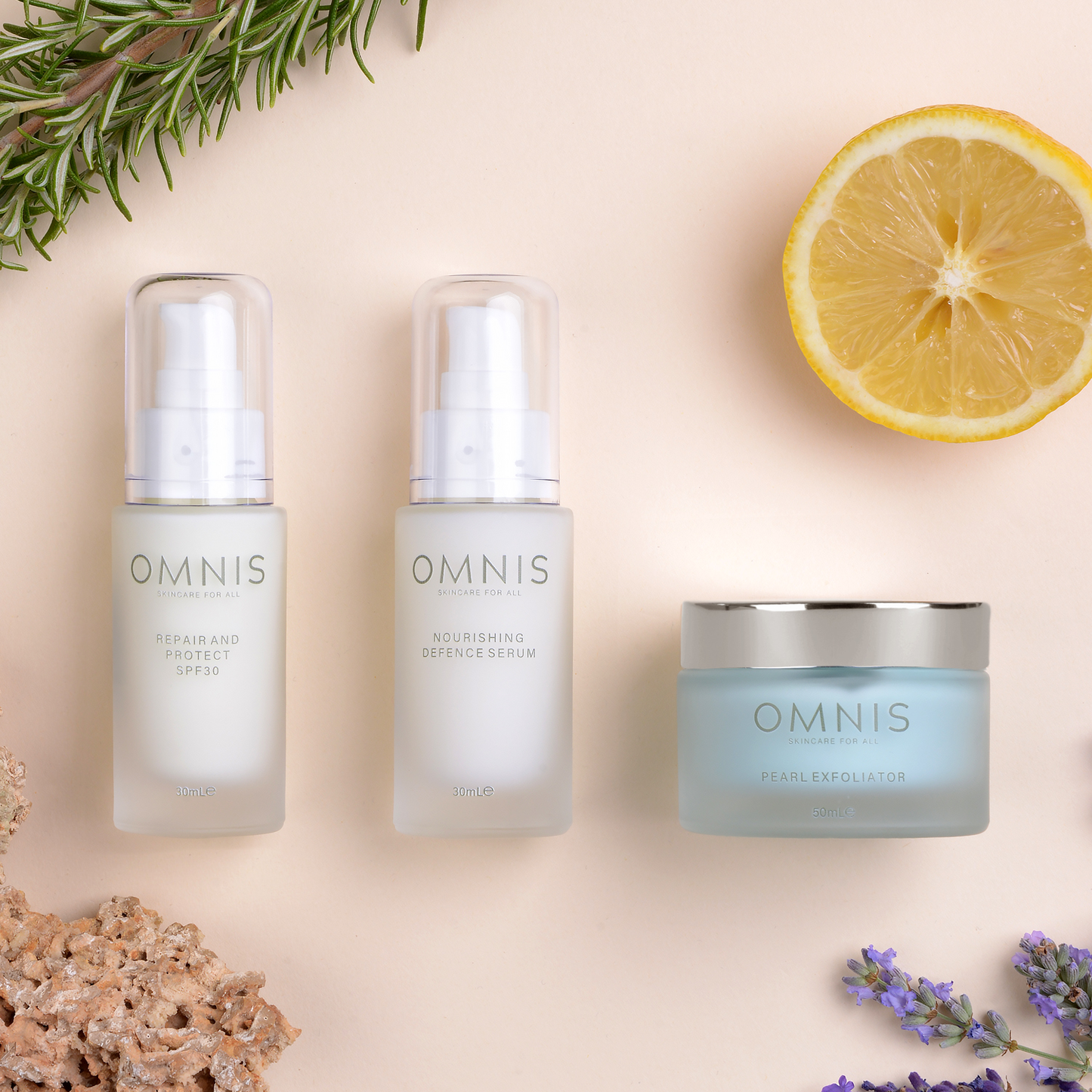 Omni Skincare set. displayed on on peach background is the 2 glass bottles a jars laid flat surrounded by lavender, rosemary and a lemon slice in each corner