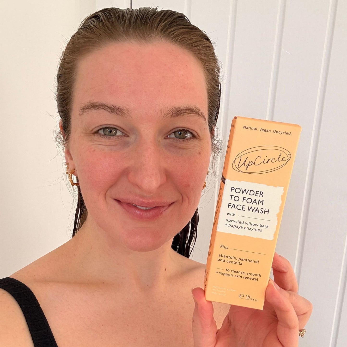 Woman holding a box of UpCircle's Powder to Foam Face Wash against a white background