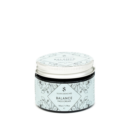 A glass jar of silvan skincare balance face cream. The small jar has an aluiminium lid and the labels are in light blue with botanical illusatrations