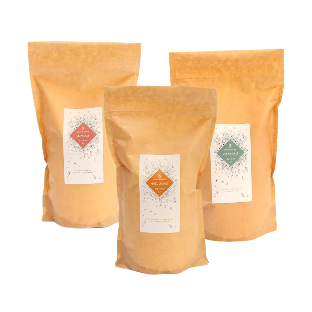 Three fully biodegradable bags  made from kraft paper, cellulose and starch.bags. They each have white labels on them. The labels read Skin Salt, Muscle Salt and Relax Salt, each with distinct colour accents: pink, orange, and green, respectively.