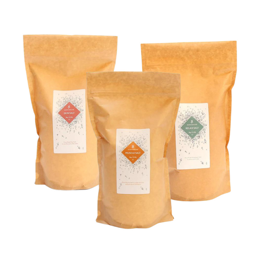 Three fully biodegradable bags  made from kraft paper, cellulose and starch.bags. They each have white labels on them. The labels read Skin Salt, Muscle Salt and Relax Salt, each with distinct colour accents: pink, orange, and green, respectively.