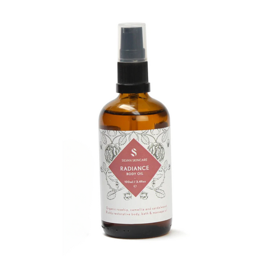 Silvan Skincare Radiance Body Oil in an amber glass bottle with a white label and a pink diamond in the middle. The bottle is against a white backdrop. Natural Body Oil
