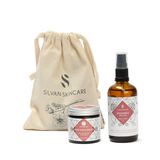 Silvan Skincare Radiance Gift Set. Vegan gifts. The gift set is photographed on a white background. You can see the branded muslin cloth bag in the background. In the foreground you can see the radiance balm and radiance body oil.