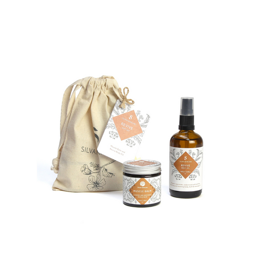 Silvan Skincare revive Gift Set. Vegan gifts. The gift set is photographed on a white background. You can see the branded muslin cloth bag in the background. In the foreground you can see the muscle balm and revive body oil.