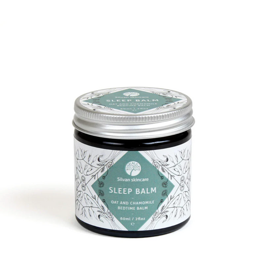 A glass jar of silvan skincare sleep balm. The small jar has an aluminium lid and the label is white with a turquoise diamond surrounded with black botanical illustrations.