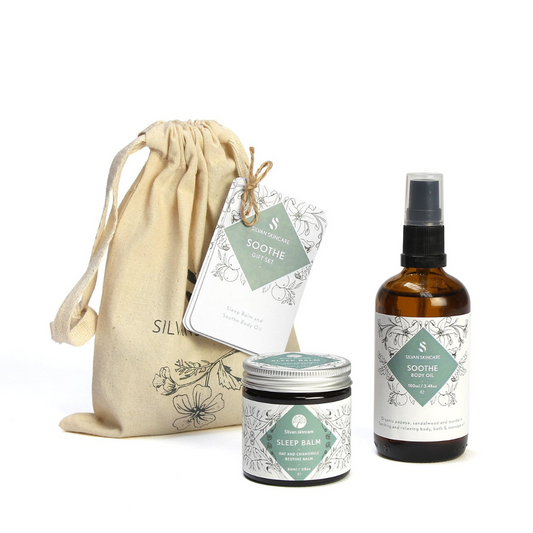 Silvan Skincare soothe Gift Set. Vegan gifts. The gift set is photographed on a white background. You can see the branded muslin cloth bag in the background. In the foreground you can see the sleep balm and soothe body oil.