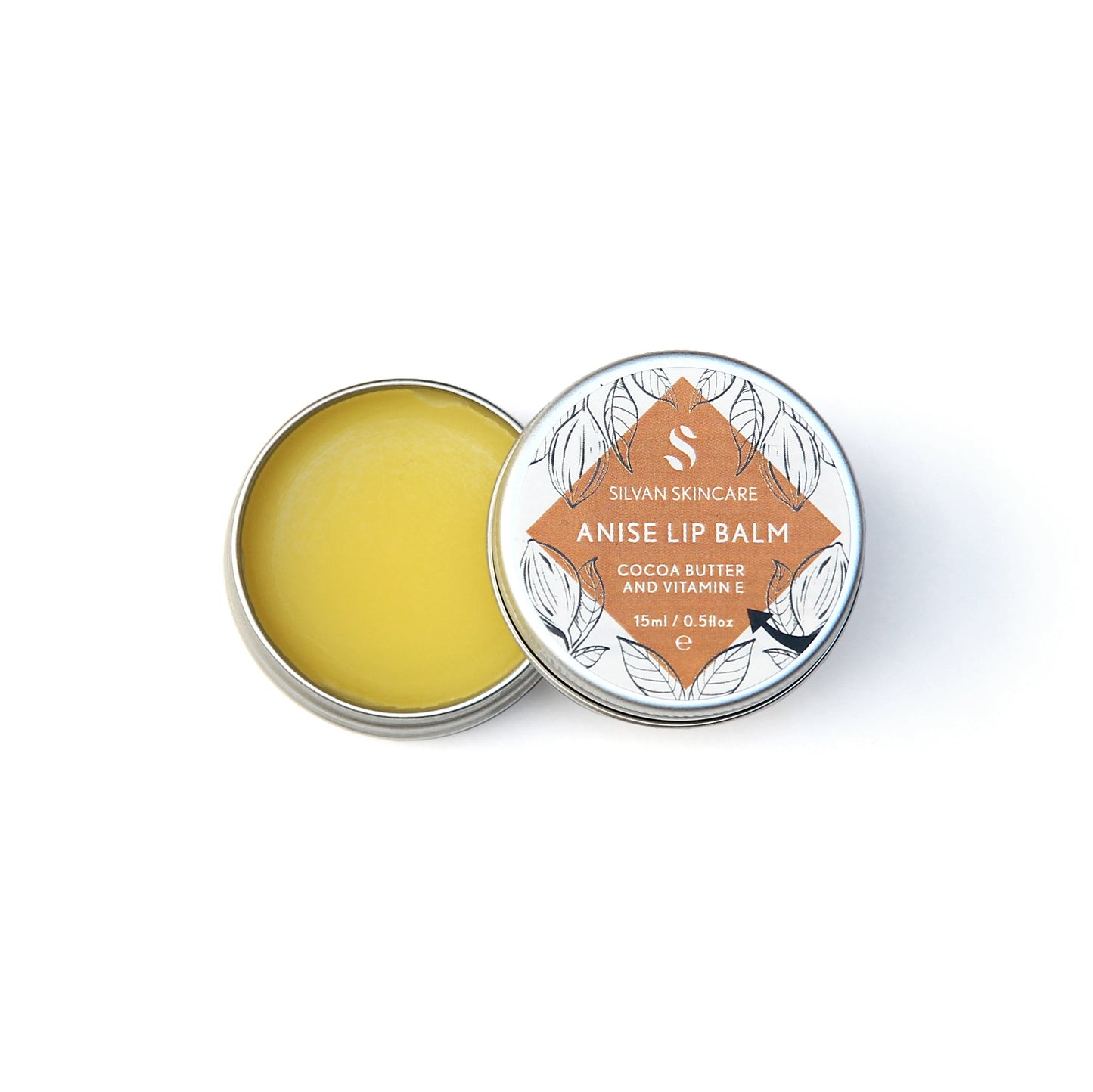 Single aluminium tin of the Silvan Skincare anise lip balm. The pot in open, showing the yellow balm inside and the lid is beside it showing the white and dark orange label