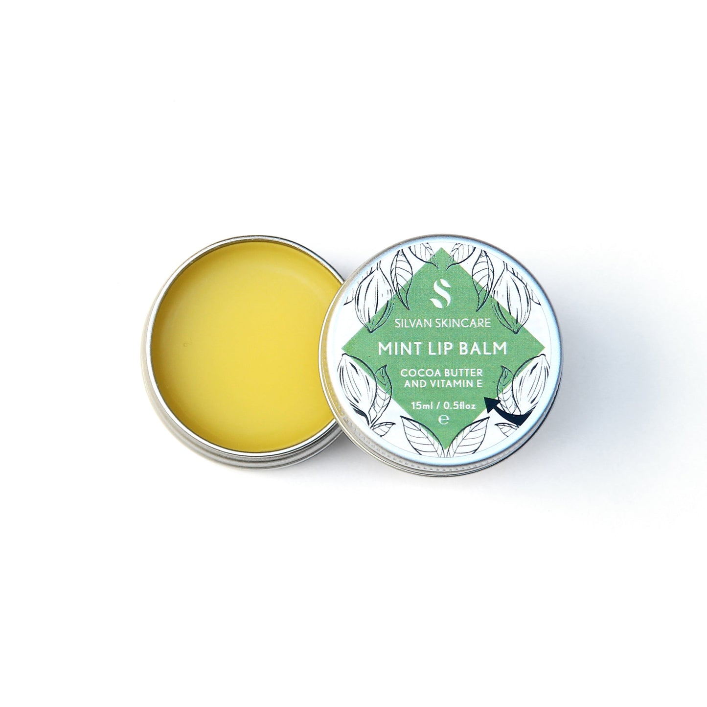 Single aluminium tin of the Silvan Skincare mint lip balm. The pot in open, showing the yellow balm inside and the lid is beside it showing the white and green label