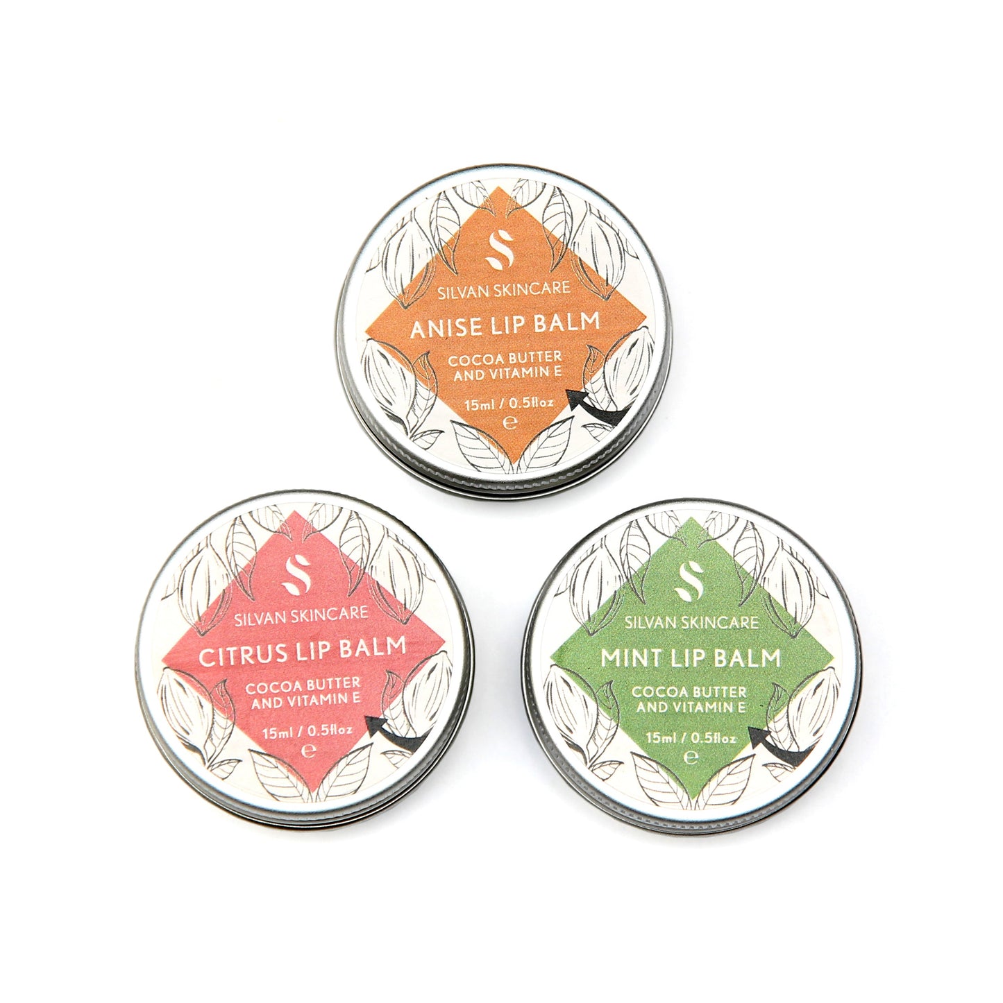 Three tins of Silvan Skincare lip balm are displayed in a square formation. Each tin has a different label (Top-Bottom-Clockwise): Anise Lip Balm (orange), Mint Lip Balm (blue-green) and Citrus Lip Balm (pink) .Each contains cocoa butter and vitamin E. Aluminium container and lid. Recyclable or Reusable.