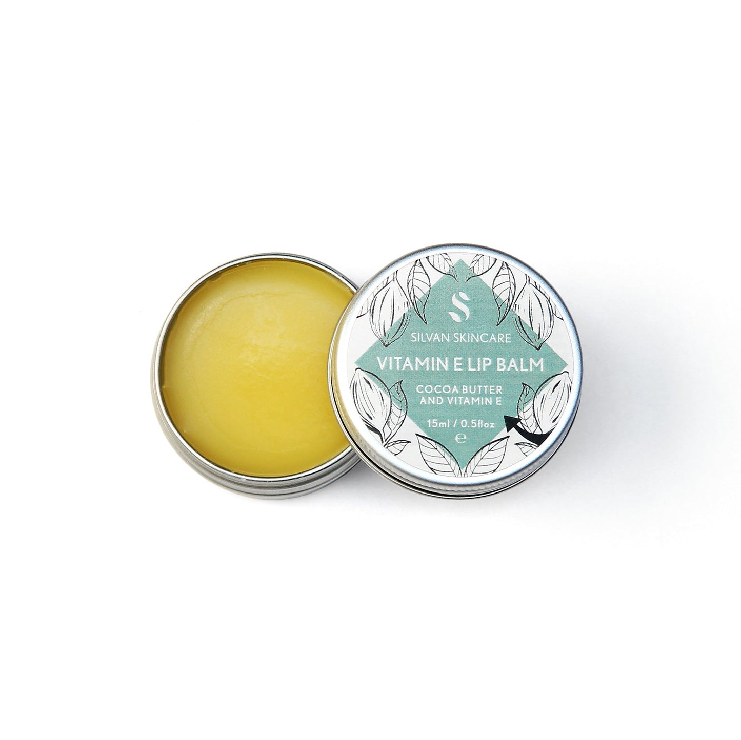 Single aluminium tin of the Silvan Skincare vitamin e lip balm. The pot in open, showing the yellow balm inside and the lid is beside it showing the white and blue label