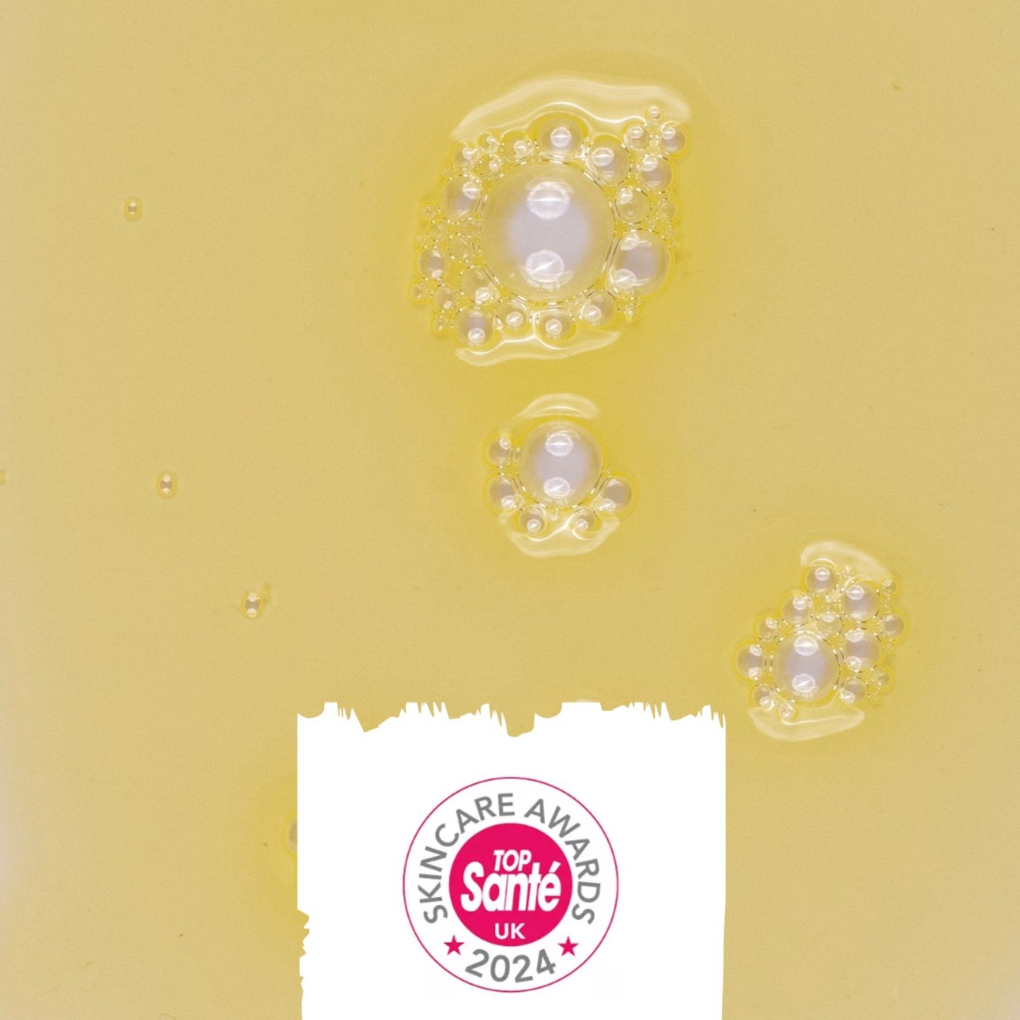 texture of the upcircle body oil on a yellow background and icon showing that it won a top sante skincare award in 2024