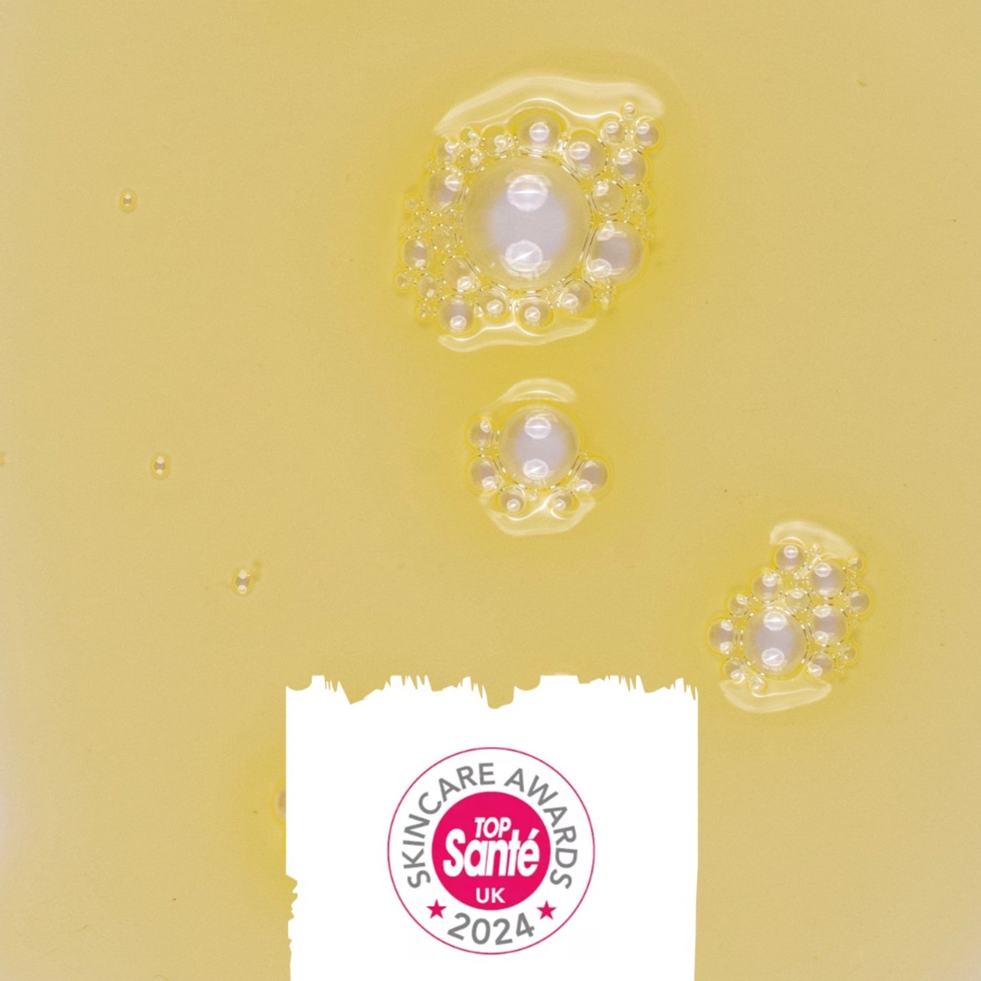 texture of the upcircle body oil on a yellow background and icon showing that it won a top sante skincare award in 2024