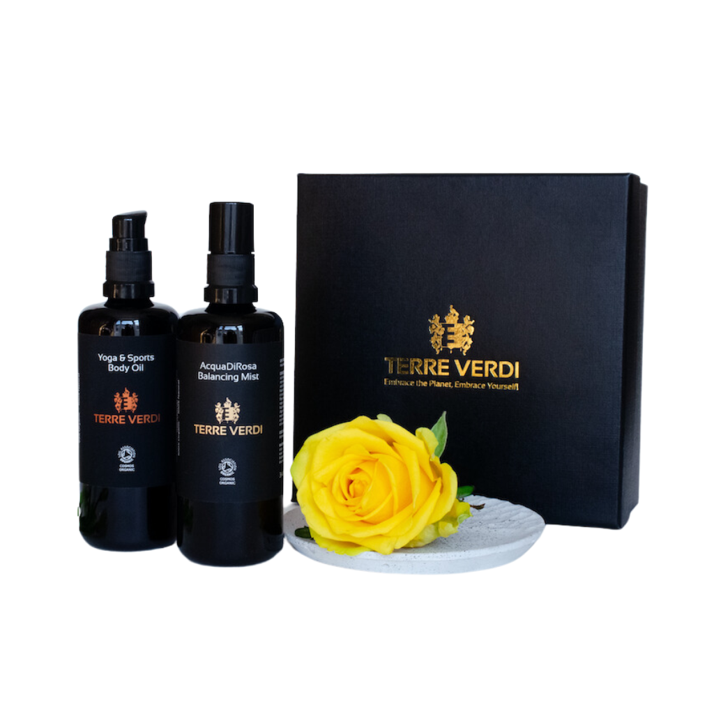 Terre Verdi Athletic Gift Set. Natural bodycare gift set. Both products are in black bottles and stand next to a luxury black box embossed in gold with the Terre Verdi logo. There is a large yellow rose sitting on a plate in front of the box.