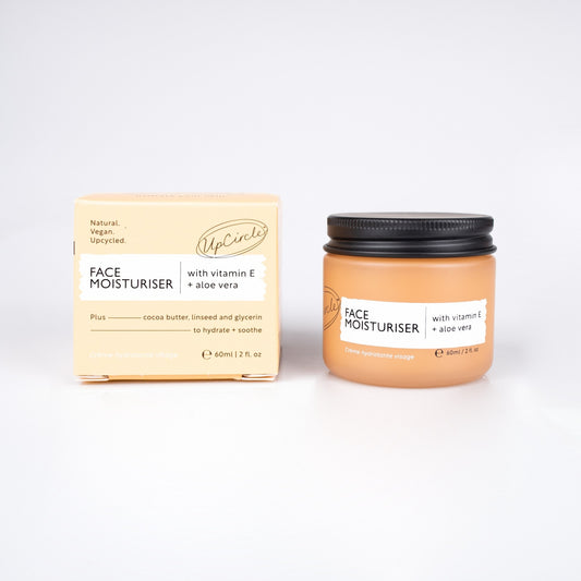 upcircle beauty face moisturiser can be seen in an orange glass jar with a black aluminium lid sitting next to the orange cardboard box the product goes in