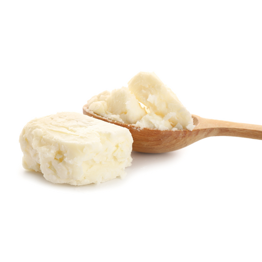 a block of raw unrefined organic shea butter next to a wooden scoop spoon with more creamy white shea butter in it