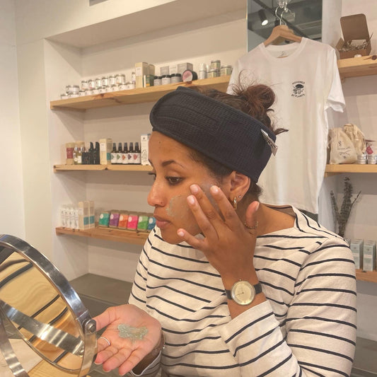 woman applying a face mask in a mirror during the facial bar, a guided skincare meets self care ritual. skincare experience hosted every month by blomma beauty with different themes.