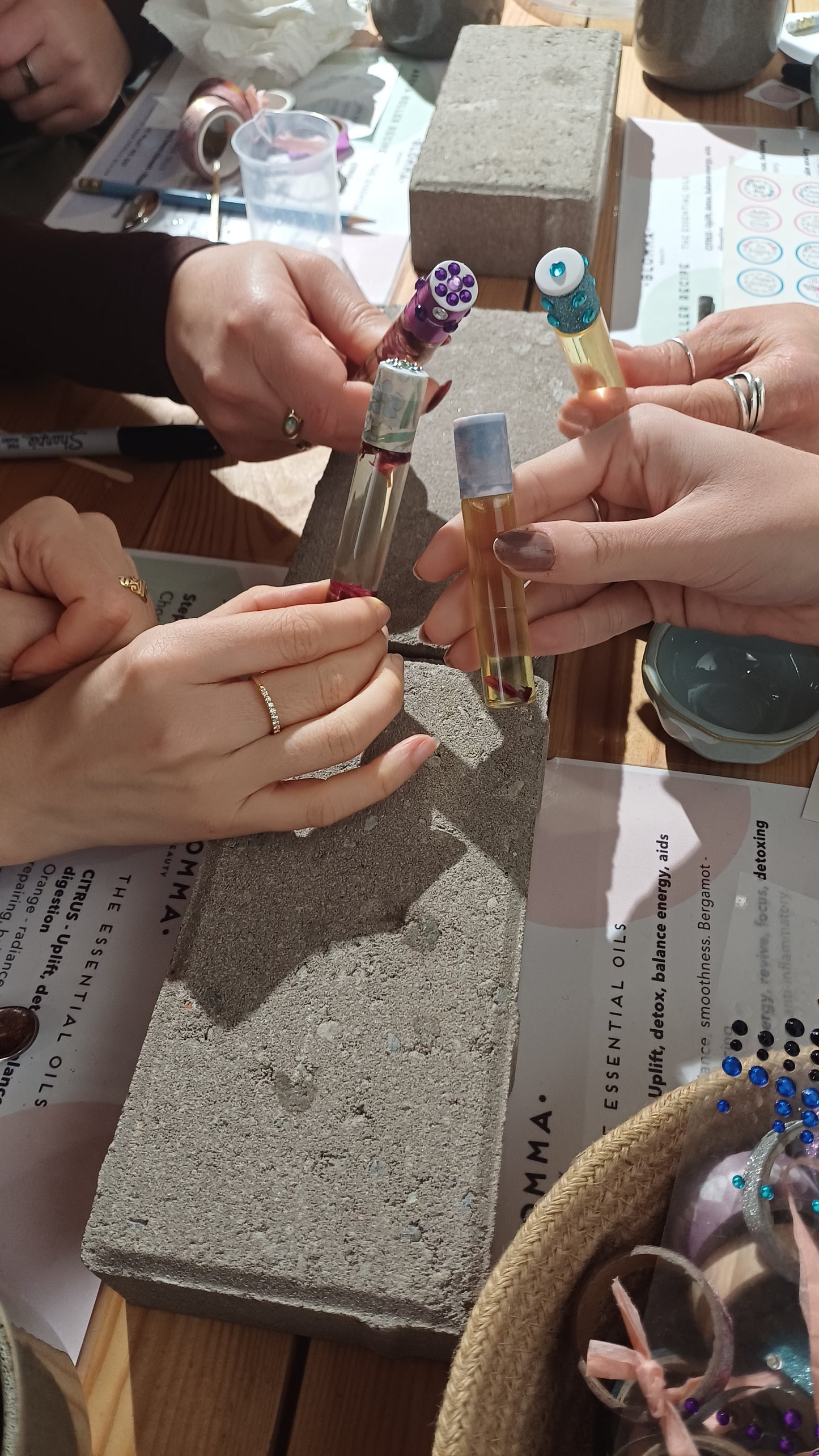 group of 4 hands each holding an aromatherapy roller they have made at the class in london