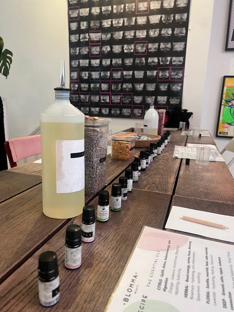 wooden table with essential oils, apricot oils and dried flowers set up for the blomma beauty aromatherapy rollerball workshop in london