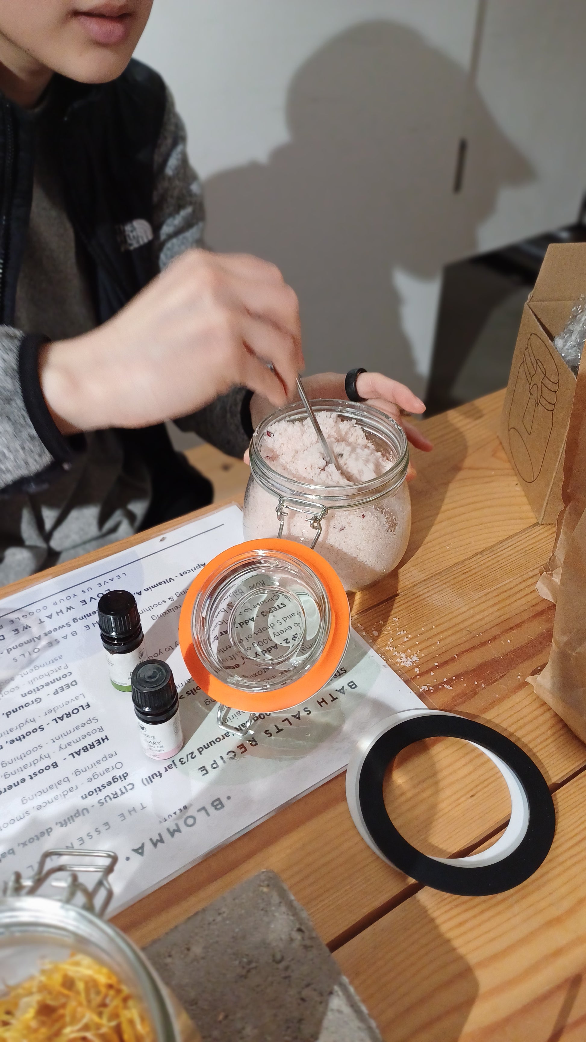 person sitting at the blomma beauty workshop table stirring up their bath salt and aromatherapy blend