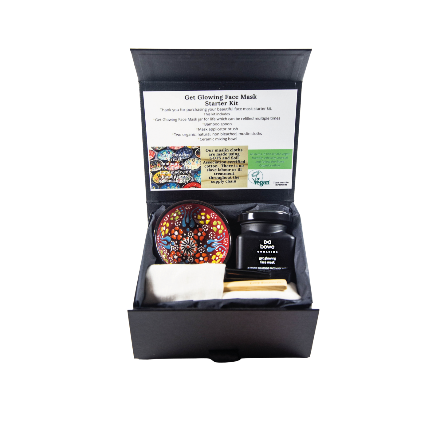 Black gift box with black tissue paper inside and contains a clay face mask gift set with a handpainted turkish style bowl a wooden mask mixing spoon, black face mask applicator brush, two organic cotton GOTS face cloths. Box is open and facing towards the camera