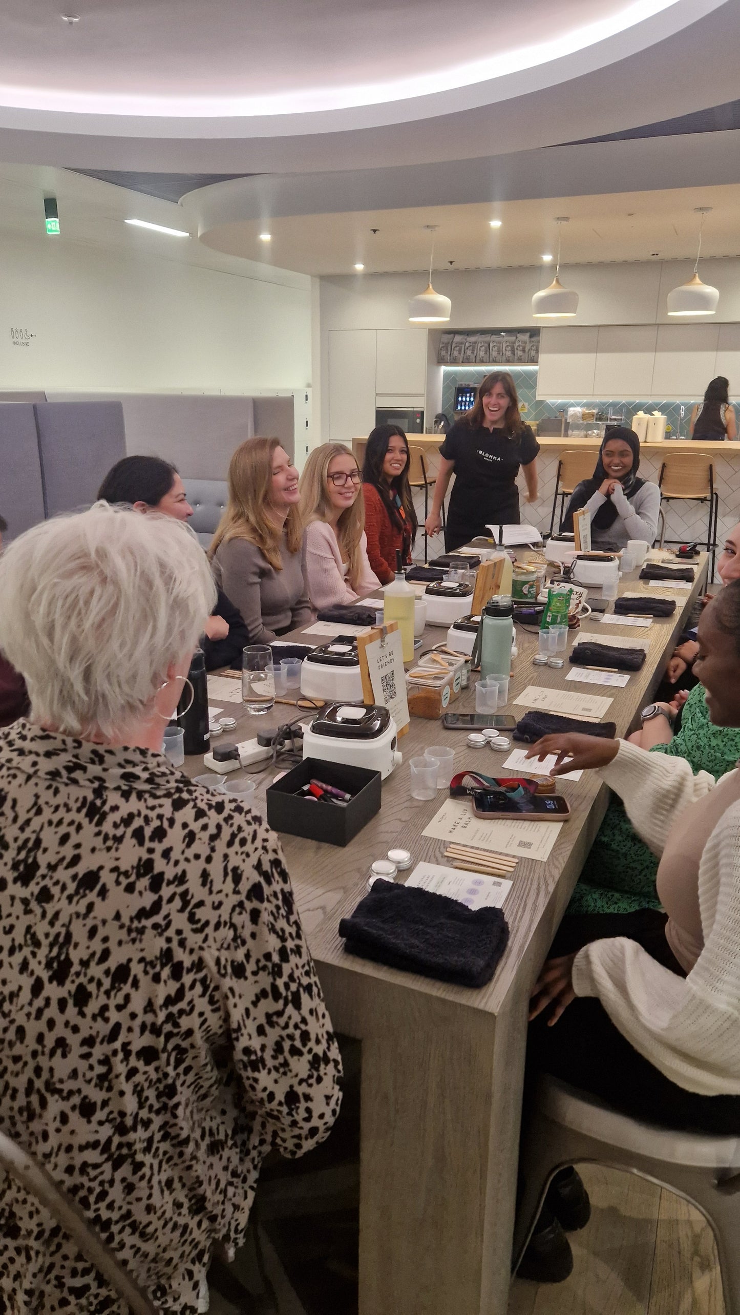 group of colleagues sitting around a table in an office in london and they are making their own lip balms as part of a team activity