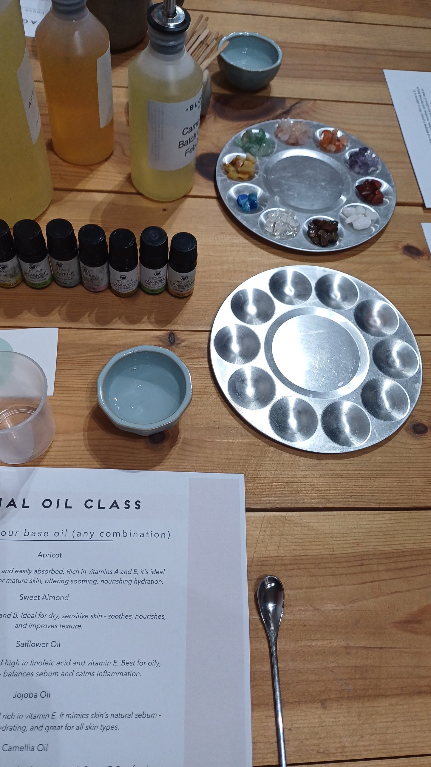 wooden table with essential oils, crystals and instructions worksheet for the face oil making class at blomma beauty