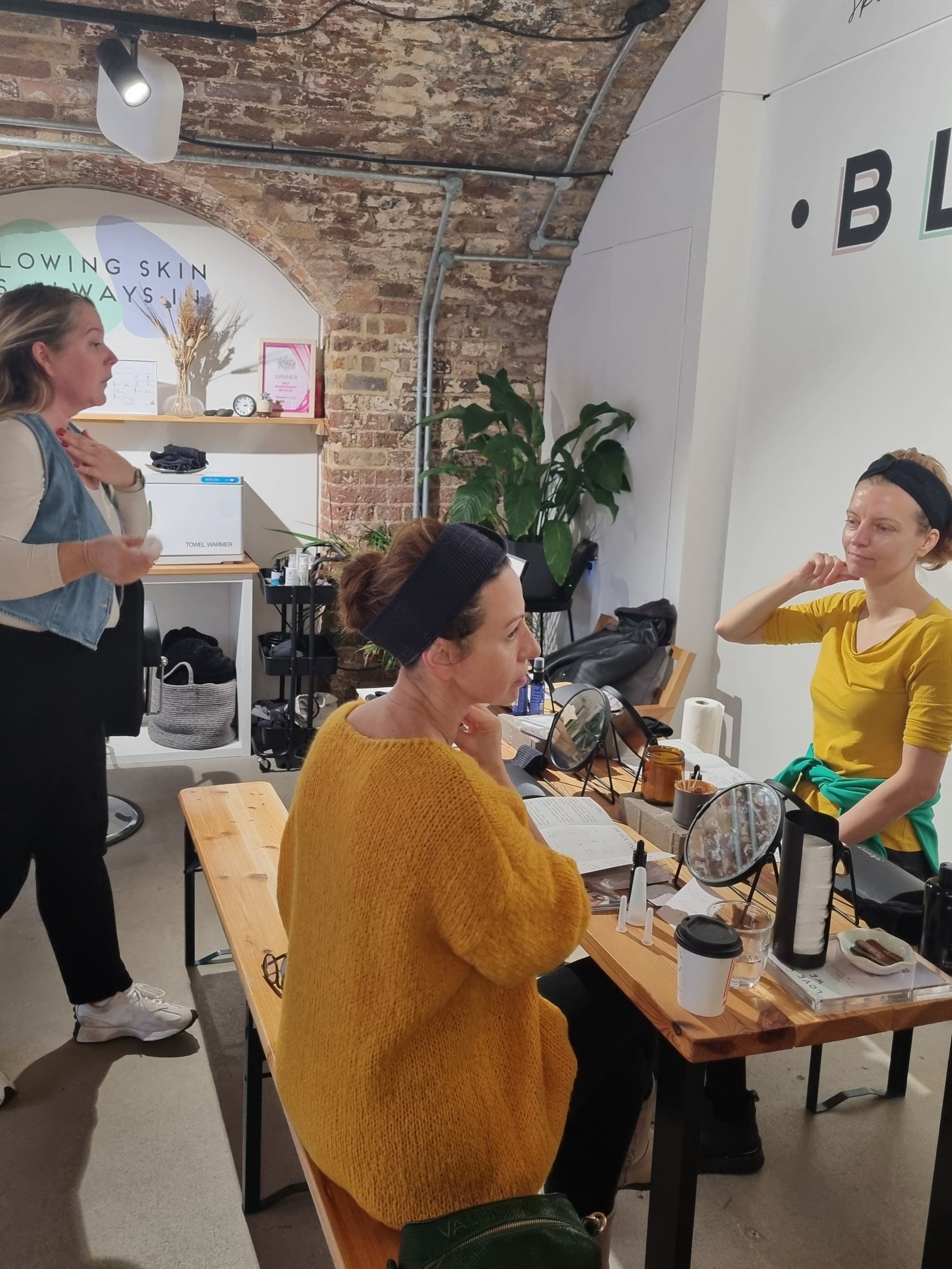 facial cupping class at blomma beauty in london. two guests can be seen copying the teacher