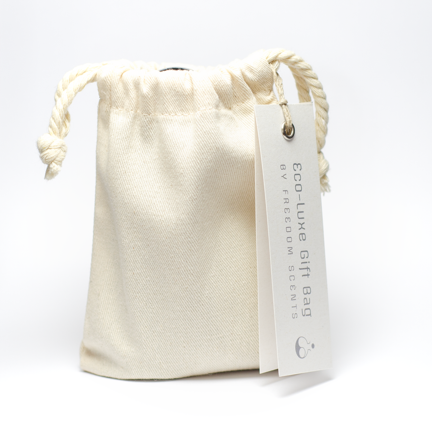 Pictured, a cotton bag with the spray and solid perfume placed inside. A tag coming off the right side that reads ‘eco-luxe gift bag’ by freedom scents