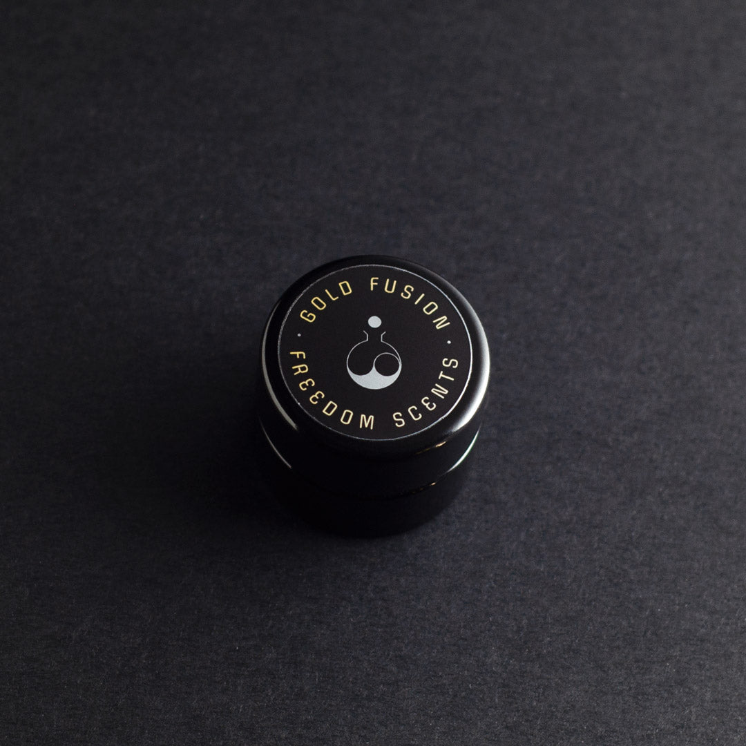 solid perfume balm on dark grey background with closed lid on the black glass jar